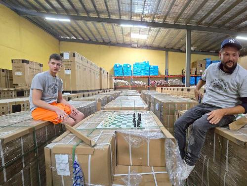 Coach Russ and Kyle on boxes full of chess sets